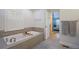 Serene bathroom showcases a soaking tub with tile surround and natural light from shuttered window at 8721 E 23Rd Ave, Denver, CO 80238