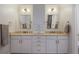 Bathroom featuring a double vanity with white cabinets, ample storage, and two mirrors at 8721 E 23Rd Ave, Denver, CO 80238