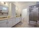 Bright bathroom featuring double vanity, white cabinets, shower with tile surround, and large soaking tub at 8721 E 23Rd Ave, Denver, CO 80238