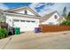 Home exterior featuring white siding, a two-car garage, a driveway, and colorful trash and recycling bins at 8721 E 23Rd Ave, Denver, CO 80238