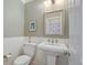 Cozy half bathroom with decorative mirror, pedestal sink, and wainscotting at 8721 E 23Rd Ave, Denver, CO 80238