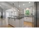Bright kitchen featuring a center island with cooktop, white cabinets, and stainless steel refrigerator at 8721 E 23Rd Ave, Denver, CO 80238