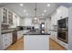 Elegant kitchen features white cabinetry, black countertops, stainless steel appliances, and center island with gas cooktop at 8721 E 23Rd Ave, Denver, CO 80238