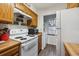 Functional kitchen featuring white appliances and wooden cabinets, alongside a cozy laundry nook at 11923 E Ford Dr, Aurora, CO 80012