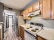 Compact kitchen with light cabinetry and appliances, view to hall with bathroom at 5745 W Atlantic Pl # 207, Lakewood, CO 80227