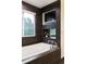 Close up of the luxurious bathroom featuring a soaking tub, a window, and dark tile at 1927 S Grant St, Denver, CO 80210