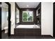 Elegant bathroom featuring a luxurious soaking tub, dark tiles, and a window view at 1927 S Grant St, Denver, CO 80210