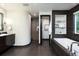 Modern bathroom featuring a deep soaking tub, sleek dark tiling, and built in shelves at 1927 S Grant St, Denver, CO 80210