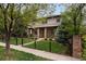 Beautiful two-story home with a black metal fence, front lawn and mature trees at 1927 S Grant St, Denver, CO 80210