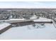 Aerial view of community school, including a playground and sports fields covered in snow at 12061 Ivy Way, Brighton, CO 80602