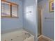Bathroom featuring a soaking tub with jets, glass-enclosed shower, and a window for natural light at 12061 Ivy Way, Brighton, CO 80602