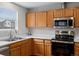 This kitchen includes a stainless steel microwave, oven, and a double-basin sink under a window at 12061 Ivy Way, Brighton, CO 80602