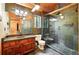 Bathroom with stone tile shower, wood ceiling, and wood vanity with stone countertop at 7221 S Brook Forest Rd, Evergreen, CO 80439