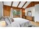 Bedroom features wood paneled walls, a vaulted ceiling, and dresser with view to the exterior at 7221 S Brook Forest Rd, Evergreen, CO 80439
