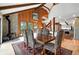 Open concept dining room with wooden ceiling beams, fireplace, and views of the surrounding woods at 7221 S Brook Forest Rd, Evergreen, CO 80439