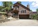 Charming brown two-story home with stone accents, a covered porch, and a two-car garage at 7221 S Brook Forest Rd, Evergreen, CO 80439