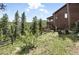 Exterior view of a hillside home featuring a multi-level deck, nestled amidst lush greenery at 7221 S Brook Forest Rd, Evergreen, CO 80439