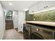 Laundry room with modern washer/dryer, farmhouse sink and stylish herringbone backsplash at 7221 S Brook Forest Rd, Evergreen, CO 80439