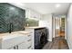 Laundry room with modern washer/dryer, farmhouse sink and stylish herringbone backsplash at 7221 S Brook Forest Rd, Evergreen, CO 80439