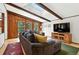 Bright living room with wood-paneled walls, exposed beams, a skylight, and a large sectional sofa at 7221 S Brook Forest Rd, Evergreen, CO 80439