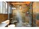Bathroom stone tiled shower with a glass door, shower head, and bench seating at 7221 S Brook Forest Rd, Evergreen, CO 80439