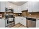 Well-equipped kitchen featuring stainless steel appliances, white cabinets, and warm brown backsplash at 710 S Clinton St # 3A, Denver, CO 80247