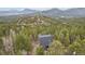 Aerial view of home surrounded by lush forest with views of distant mountains, showcasing privacy and natural beauty at 11390 Shimley Rd, Golden, CO 80403