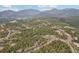 Houses surrounded by trees, showcasing winding roads and distant mountains, highlighting a serene neighborhood environment at 11390 Shimley Rd, Golden, CO 80403