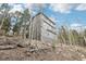 Three-story home on a hillside, nestled among trees, displaying a modern design and gray siding under a partly cloudy sky at 11390 Shimley Rd, Golden, CO 80403