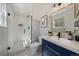 Bright bathroom featuring a modern vanity with navy blue cabinets, gold accents, and a glass-enclosed shower at 12155 W 68Th Pl, Arvada, CO 80004