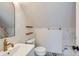 Cozy bathroom with a sink, toilet, decorative shelves, and stylish black and white patterned flooring at 2572 Chase St, Edgewater, CO 80214