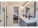 Bathroom with double sink vanity, framed mirrors, updated lighting, and an open doorway to the bedroom at 2572 Chase St, Edgewater, CO 80214