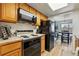 Well-equipped kitchen featuring a black refrigerator, stove and oven, light wood cabinetry, and a view of the dining area at 540 S Forest St # 5-204, Denver, CO 80246