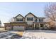 Two-story house with stone accents and a three-car garage in a snowy neighborhood at 1669 S De Gaulle Way, Aurora, CO 80018