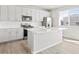 Modern kitchen with white cabinets, stainless steel appliances, a central island, and light hardwood floors at 564 Red Rock Pl, Brighton, CO 80601