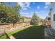 Fenced backyard with green lawn, large shade trees, and flower planters at 14049 Detroit Dr, Thornton, CO 80602
