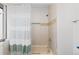 Bright bathroom featuring a tub with tiled walls, a shower head, and a modern striped shower curtain at 12017 W 54Th Dr, Arvada, CO 80002