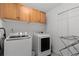 Laundry room featuring wood cabinets over a front loading washer and dryer at 12017 W 54Th Dr, Arvada, CO 80002