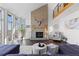 Bright living room with a brick fireplace, hardwood floors, and large windows offering abundant natural light at 12017 W 54Th Dr, Arvada, CO 80002