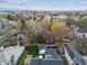 Aerial view of a brick home with lush backyard and neighborhood trees; city skyline beyond at 10 Cherry St, Denver, CO 80220