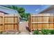 Wooden gate opens to a backyard area with gravel, stepping stones and beautiful flowerbeds at 235 N 12Th Ave, Brighton, CO 80601