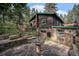 Charming stone and log cabin exterior with stone patio, green trim, and stone steps at 5672 Santa Clara Rd, Indian Hills, CO 80454