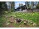 Backyard fire pit nestled within landscaped yard with view of cabin and forest backdrop at 5672 Santa Clara Rd, Indian Hills, CO 80454