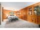 Spacious carpeted bedroom with wooden walls, built-in display cabinets, and a plaid bench at 5672 Santa Clara Rd, Indian Hills, CO 80454