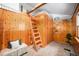 Cozy bedroom with wooden walls, lofted bed, ladder, shelving, and bench seating at 5672 Santa Clara Rd, Indian Hills, CO 80454