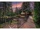 Charming cabin exterior with stone walkway, inviting patio, and lush green surroundings at twilight at 5672 Santa Clara Rd, Indian Hills, CO 80454