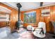 Cozy living room featuring a wood-burning stove, comfortable seating, and a view of the surrounding woods at 5672 Santa Clara Rd, Indian Hills, CO 80454