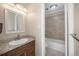 Bathroom features a light grey tiled shower/tub and a brown vanity with light countertops at 1496 S Pierson St # 116, Denver, CO 80232
