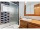 Bathroom with blue tile, shower/tub combo, and wood vanity at 1104 Elmer Dr, Northglenn, CO 80233