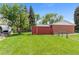 Expansive lawn and a functional red shed enhance this home's backyard, providing ample space for outdoor activities at 6025 Johnson Way, Arvada, CO 80004
